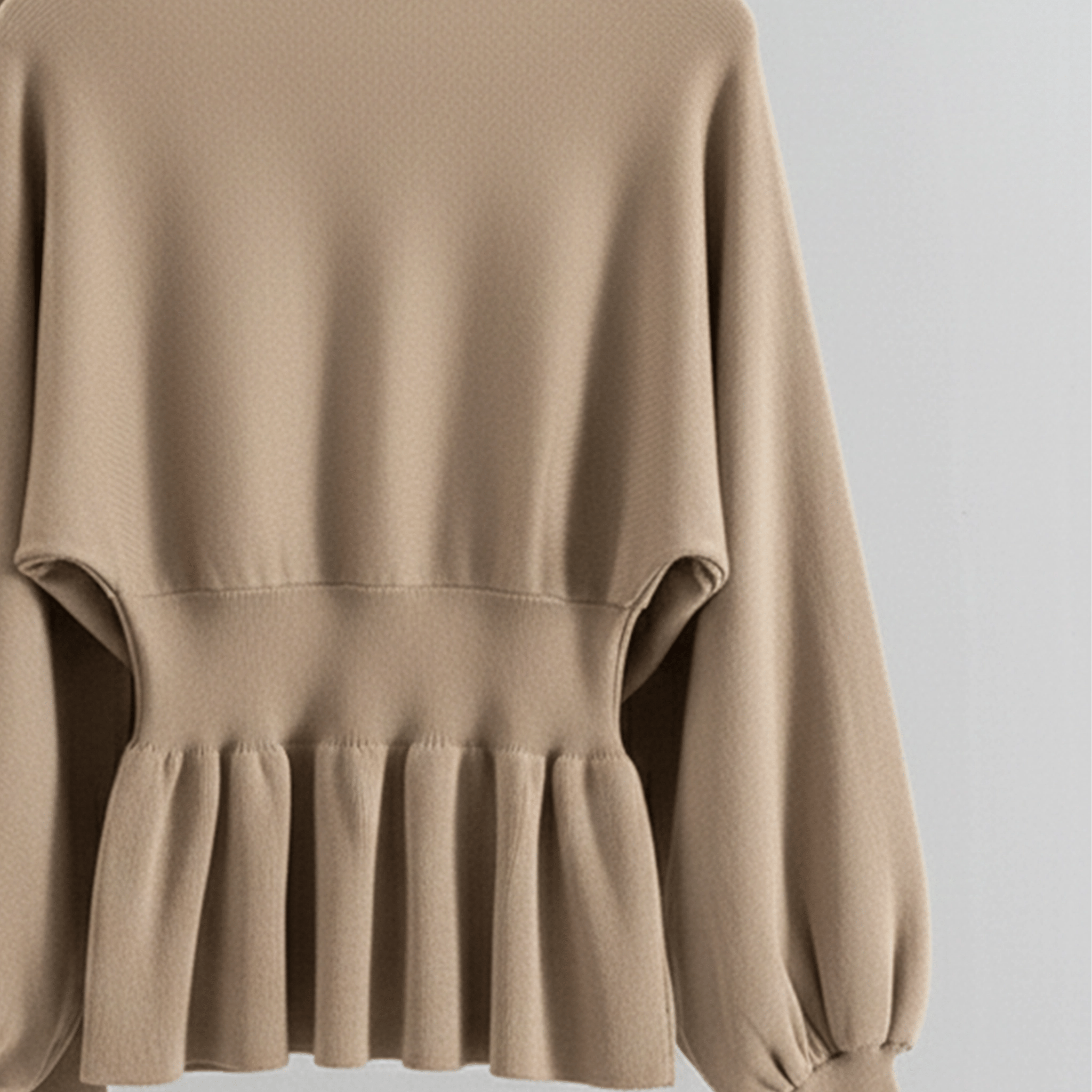Beige sweater with ruffled hem on a light gray background