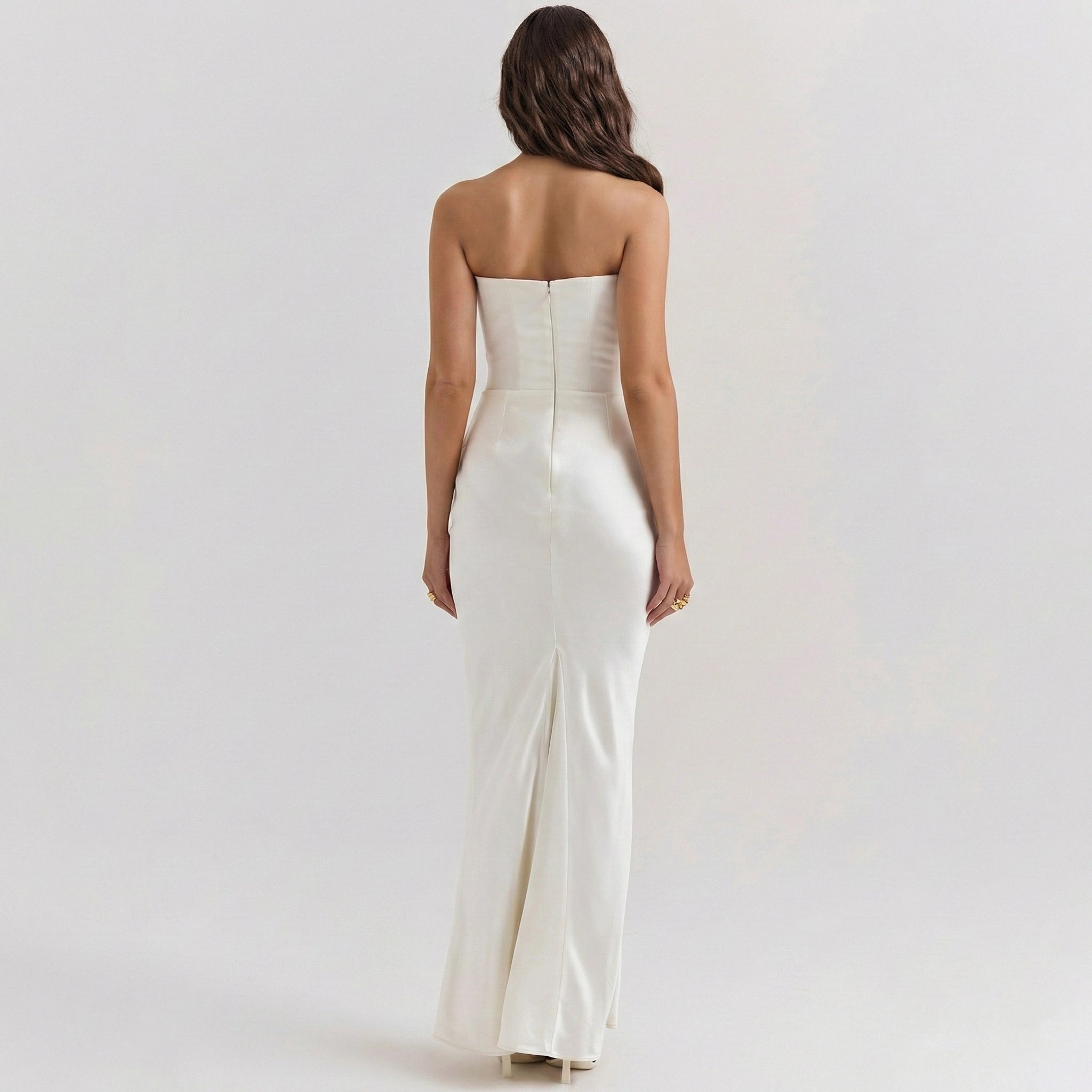 Woman wearing a strapless white evening gown on a plain background