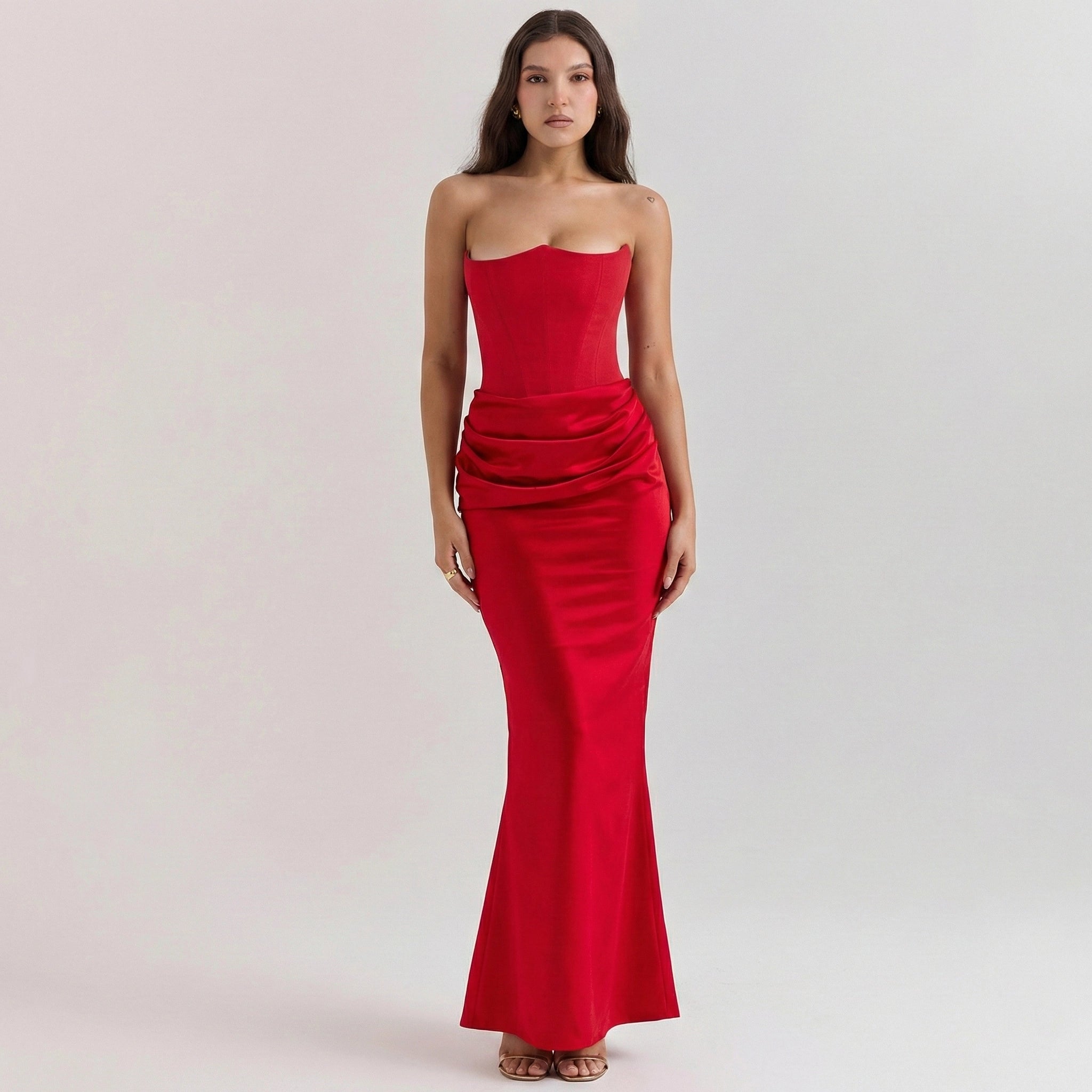 Woman wearing a strapless red evening gown on a light pink background