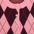 Close-up of a pink and black argyle patterned fabric with buttons.