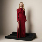 Woman in a red off-shoulder gown standing on black steps against a beige background