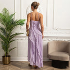 Woman in a lavender dress standing in a stylish room with a plant and chair.