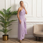 Woman in a lavender dress standing in a stylish room with decorative wall and plant.