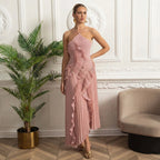 Woman in a pink one-shoulder dress standing in an elegant room with decorative wall and plant.