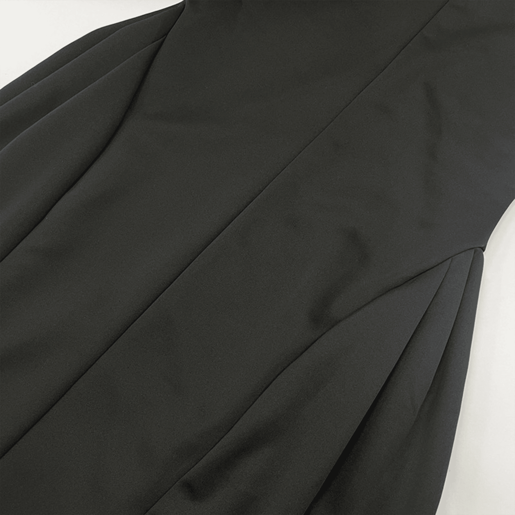 Close-up of a black garment with draped fabric on a white background