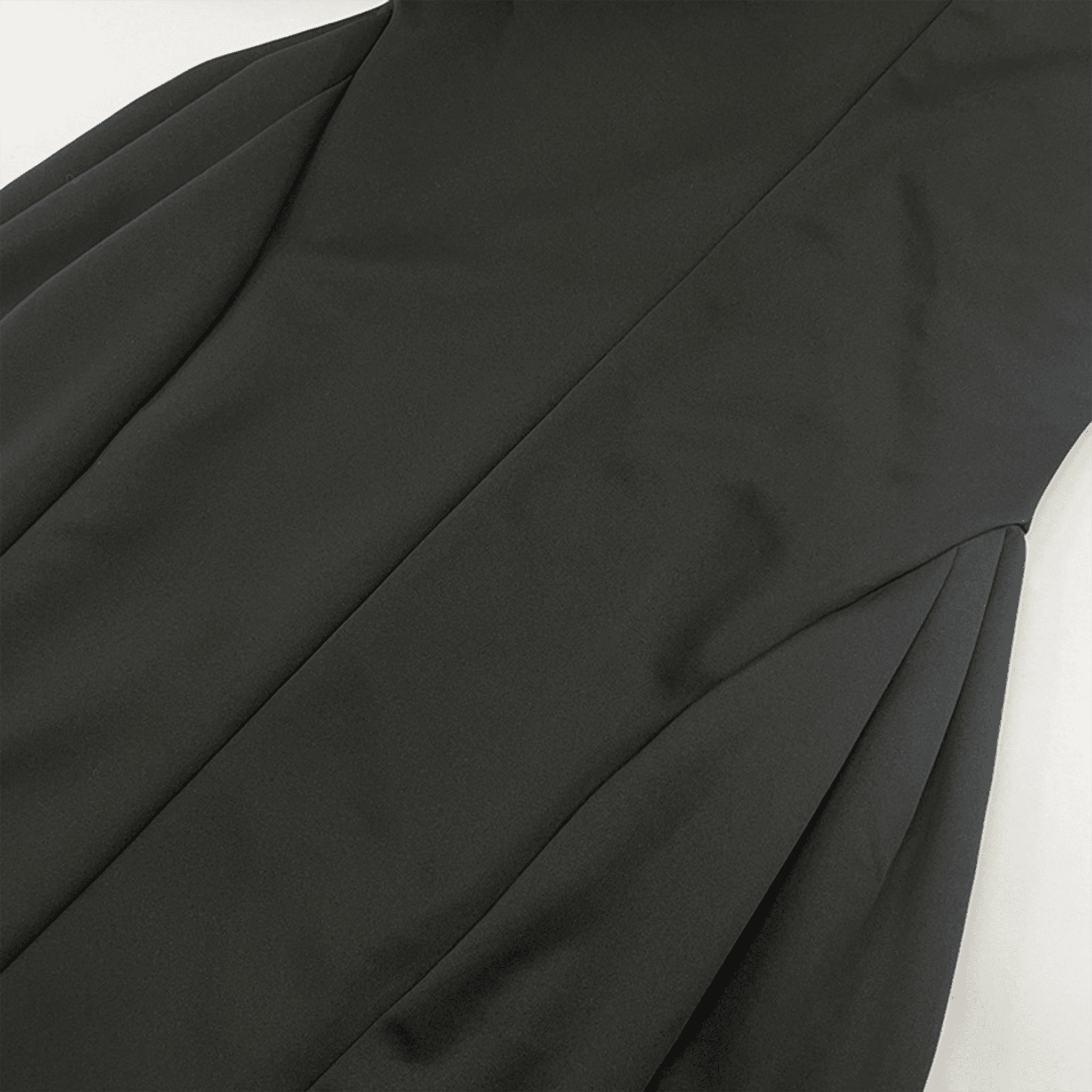 Close-up of a black garment with draped fabric on a white background
