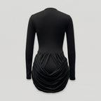 Black long-sleeve dress with a draped skirt on a light gray background
