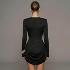 Black dress with long sleeves and a ruched skirt on a gray background