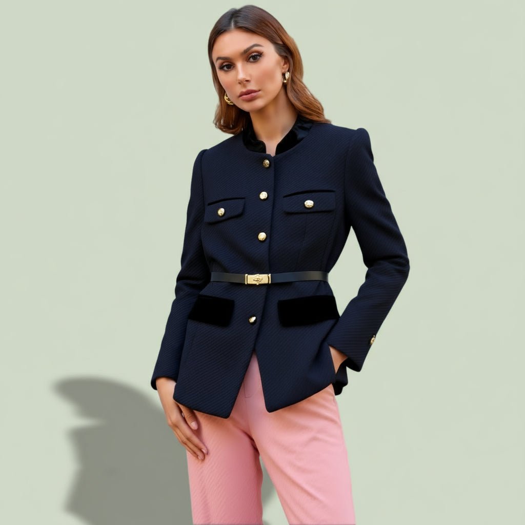 Woman wearing a navy blazer with gold buttons and pink pants on a light green background