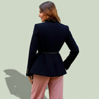 Woman wearing a black blazer and pink pants against a light green background