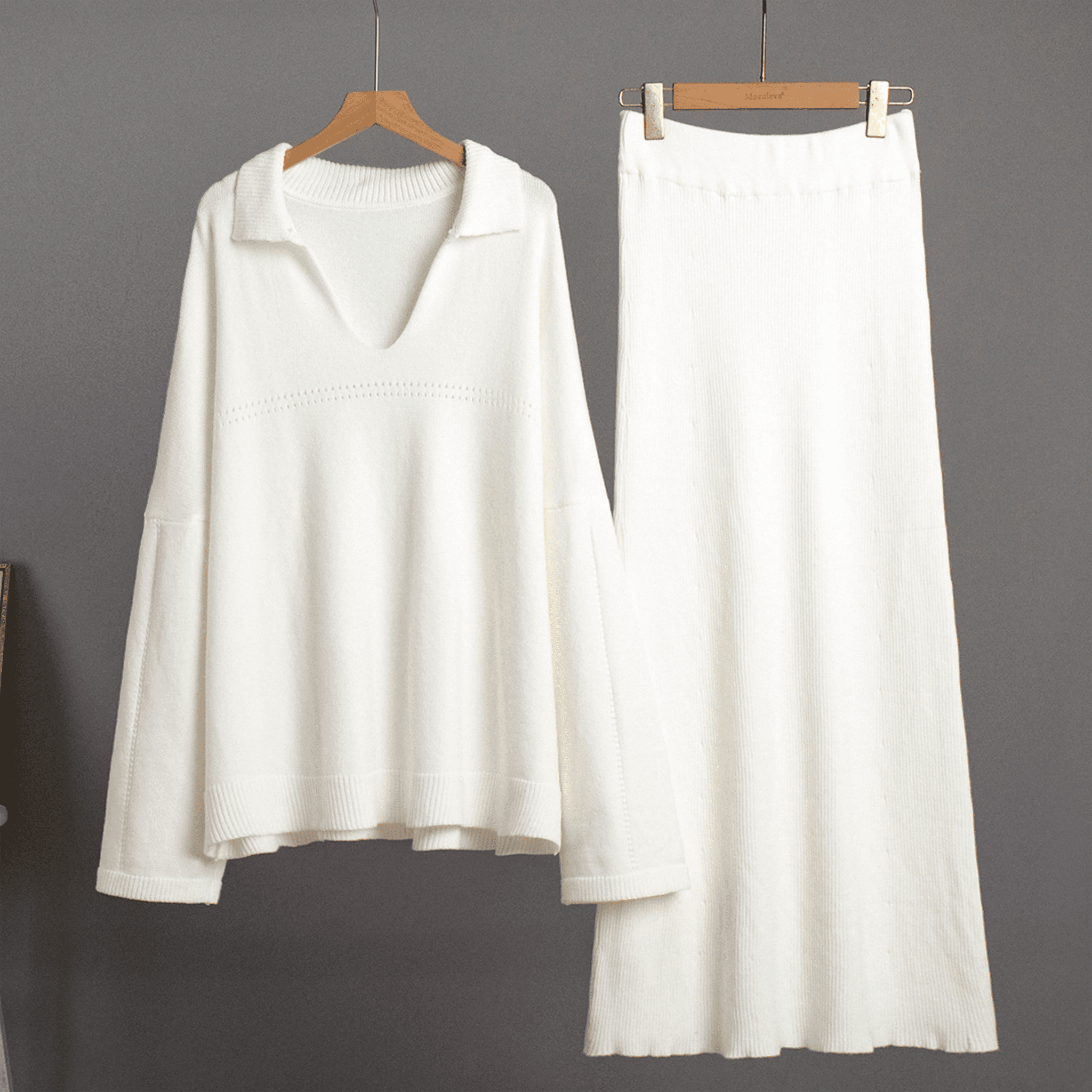 White long-sleeve top and skirt set on hangers against a gray background