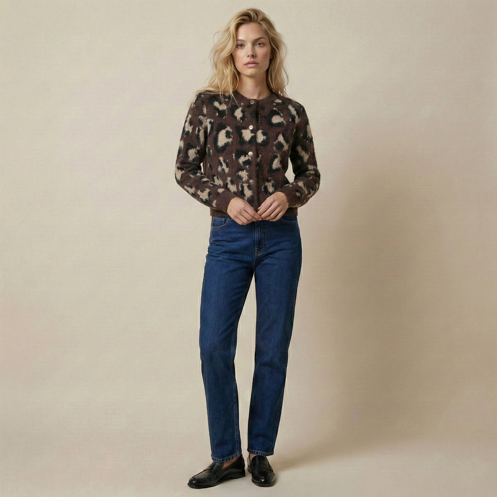 Woman wearing a patterned shirt and blue jeans against a beige background