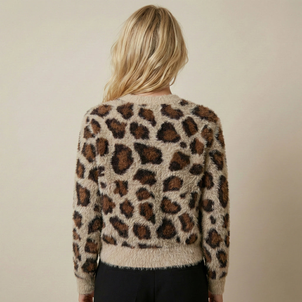 Person wearing a leopard print sweater against a plain background