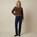 Woman wearing a leopard print jacket and dark jeans on a beige background