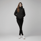 Woman wearing a black puffer jacket and leggings on a gray background