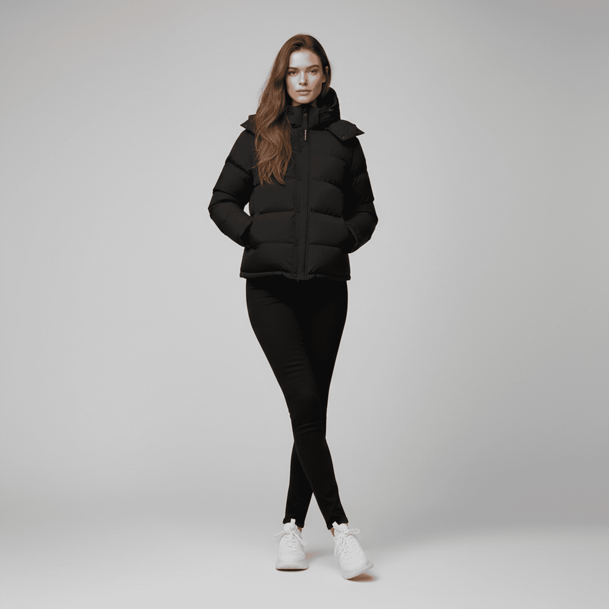 Woman wearing a black puffer jacket and leggings on a gray background