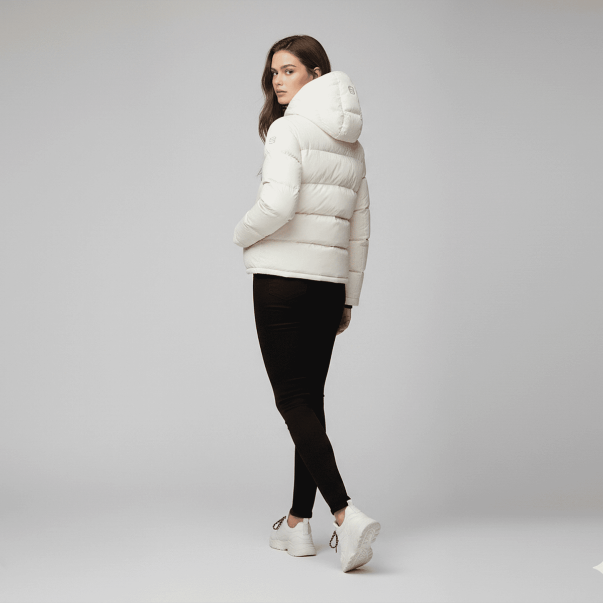Woman wearing a white puffer jacket on a gray background