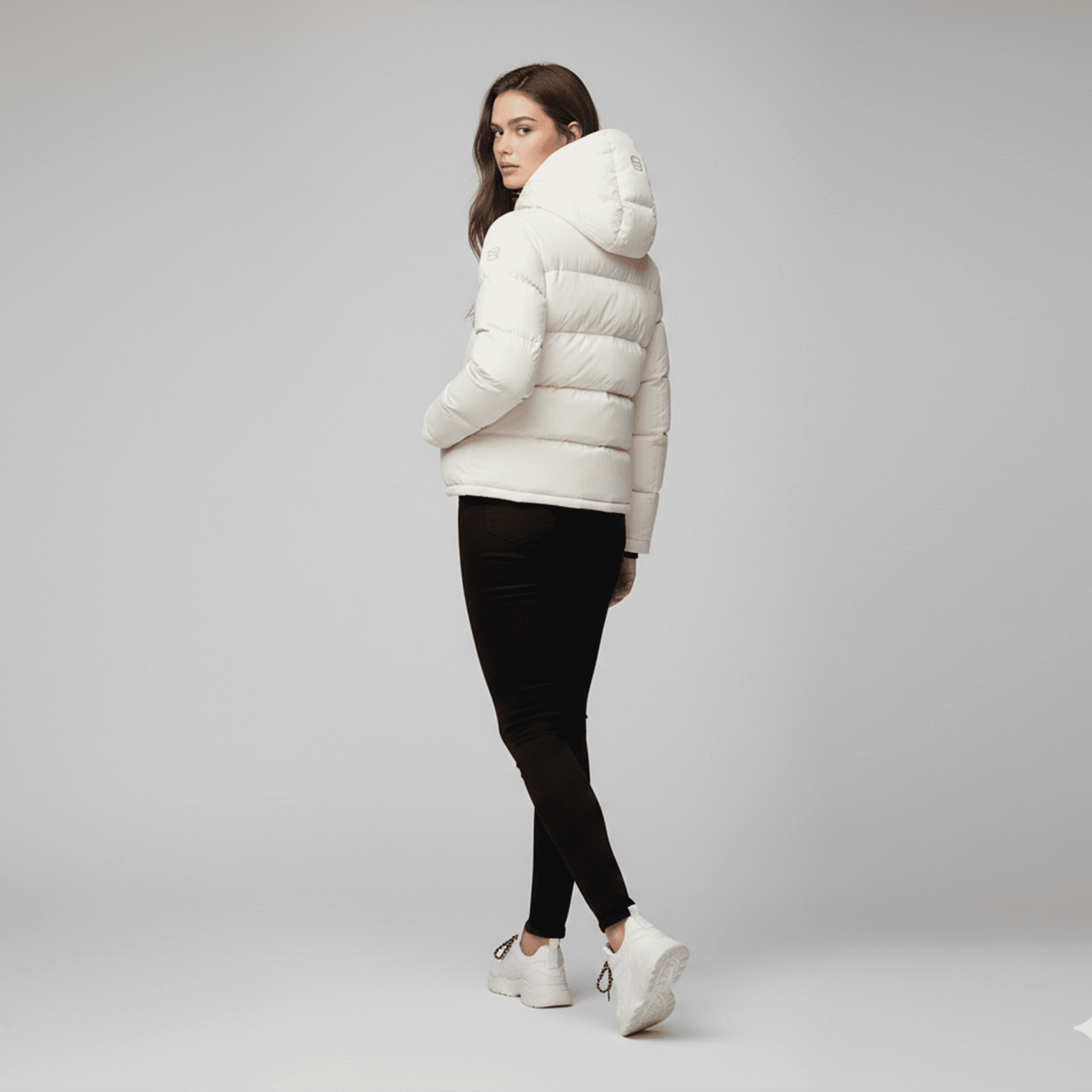Woman wearing a white puffer jacket on a gray background