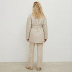 Person wearing a beige puffer coat and pants against a white background