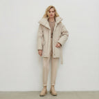 Woman wearing a beige coat and pants against a white background