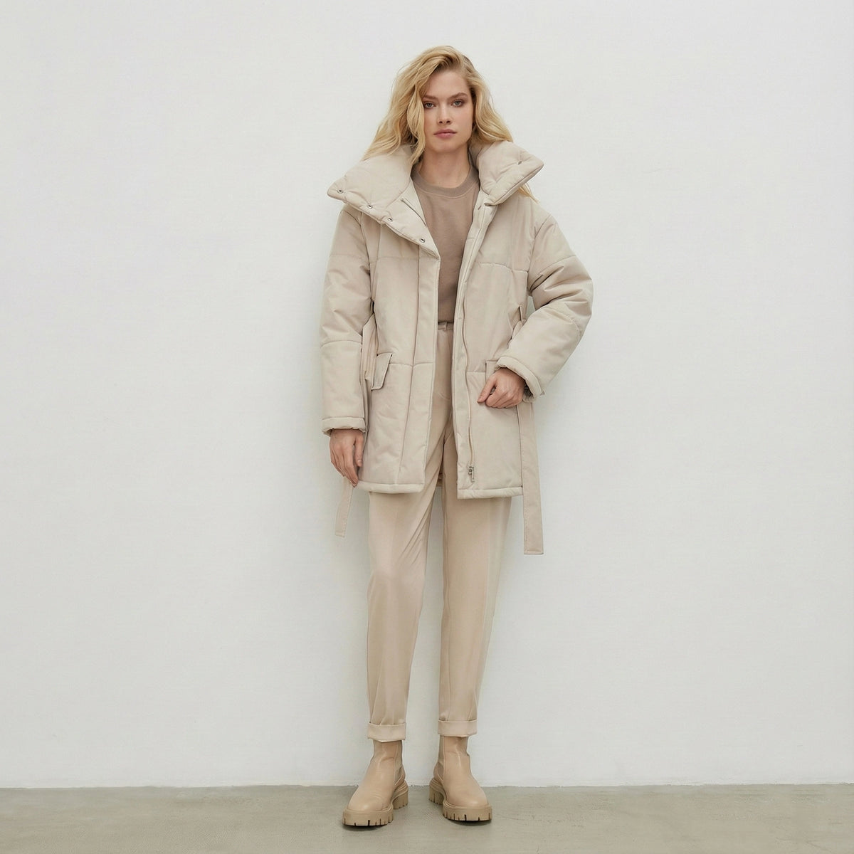 Woman wearing a beige coat and pants against a white background