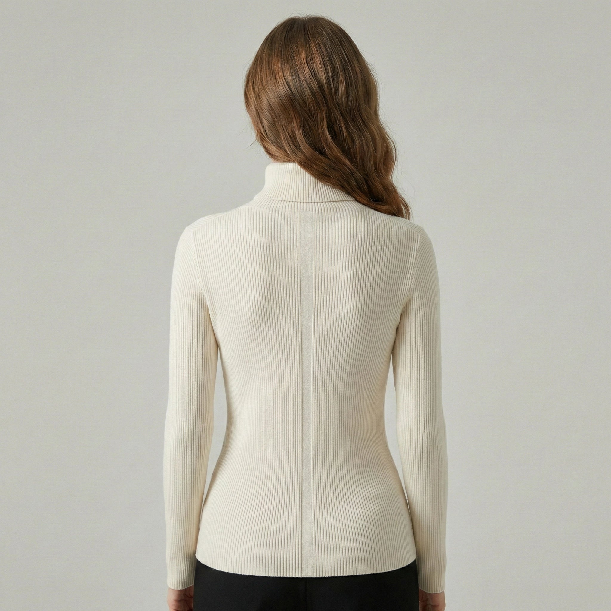 Woman wearing a cream ribbed sweater against a plain background