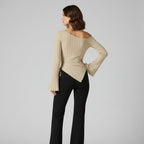 Woman wearing a beige ribbed sweater and black pants on a gray background