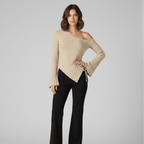 Woman wearing a beige ribbed sweater and black pants on a gray background