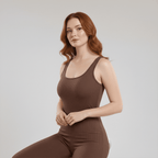 Woman wearing a brown ribbed tank top and leggings on a light gray background