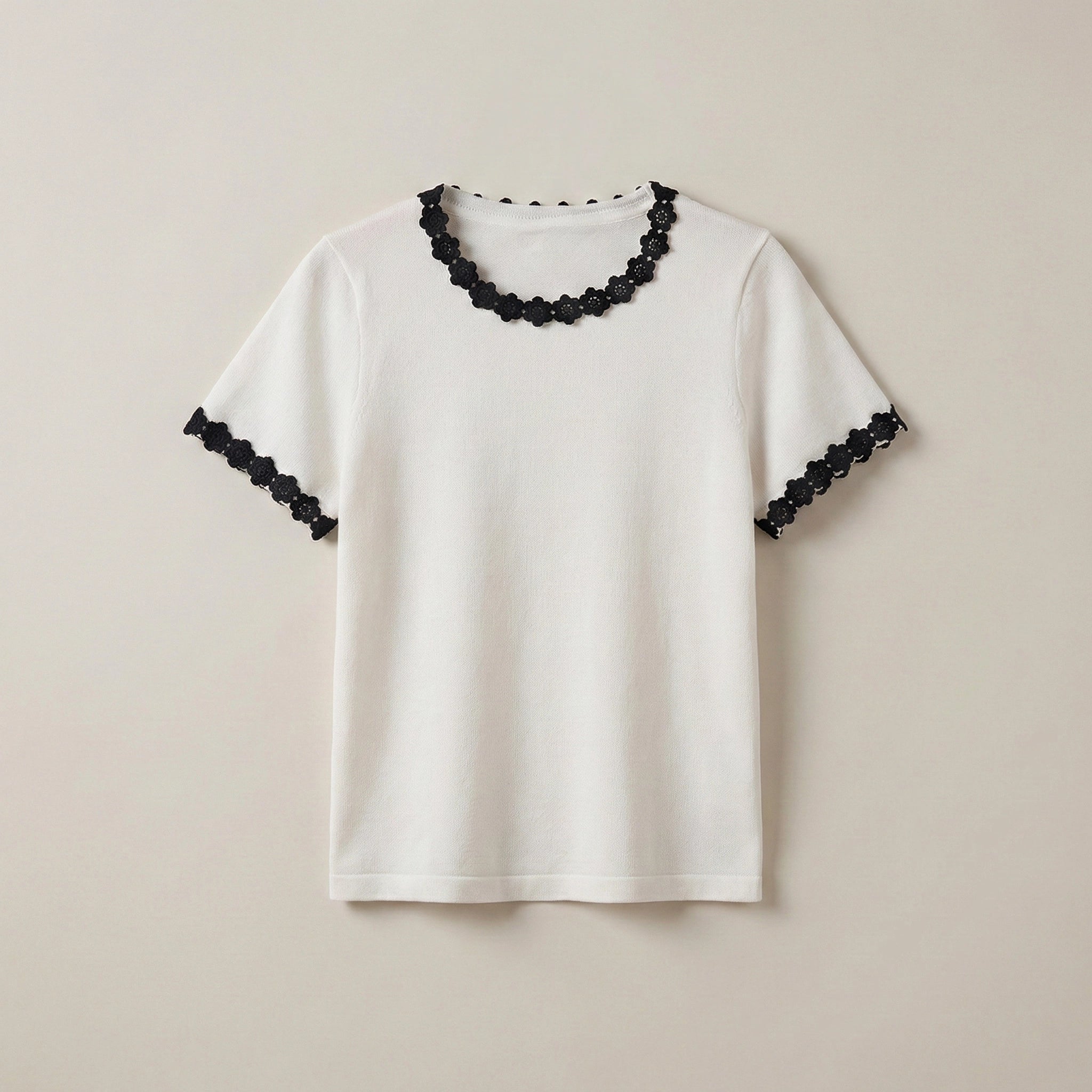 White t-shirt with black lace details on a beige background