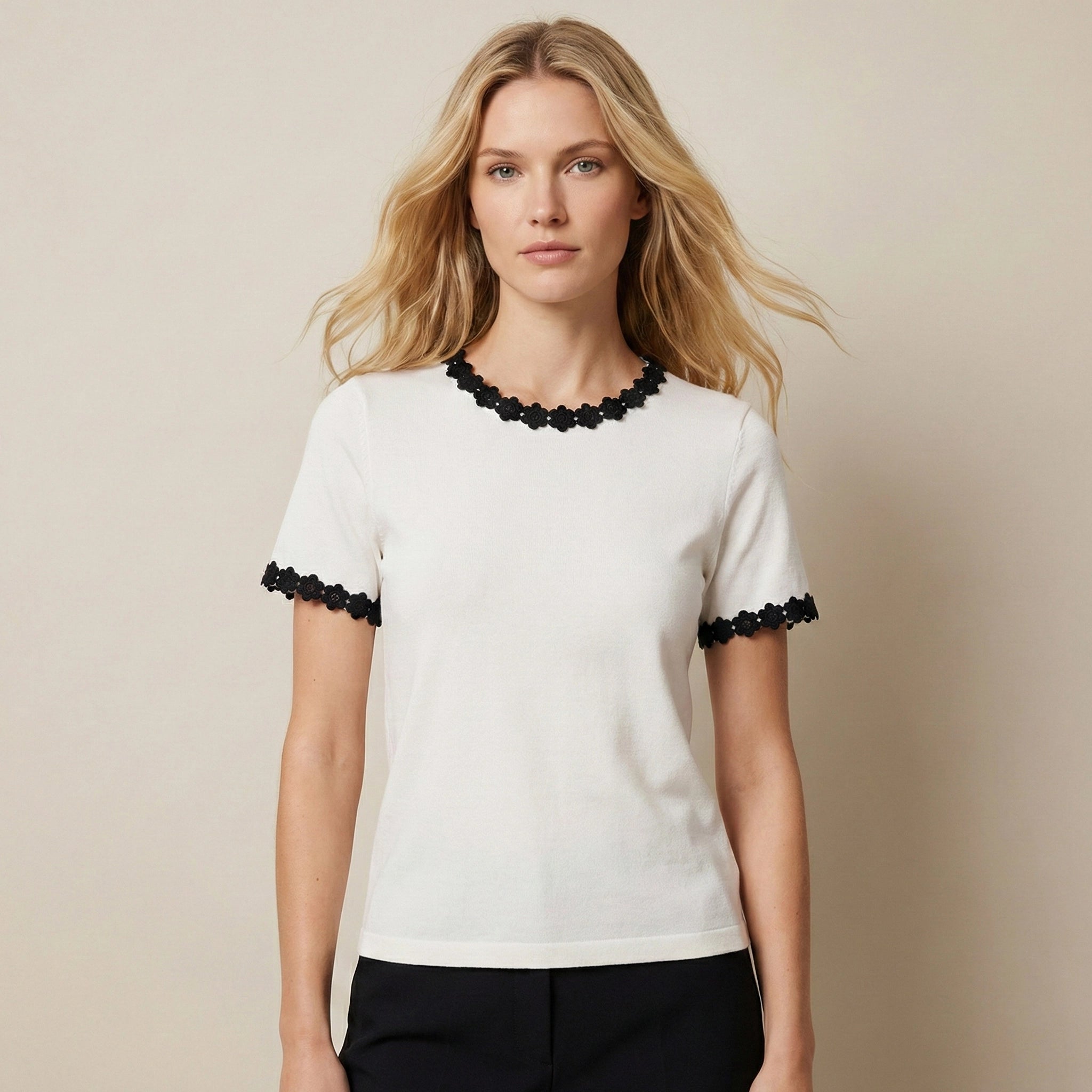 Woman wearing a white top with black trim against a beige background