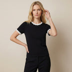 Woman wearing a black top with white lace trim on a beige background