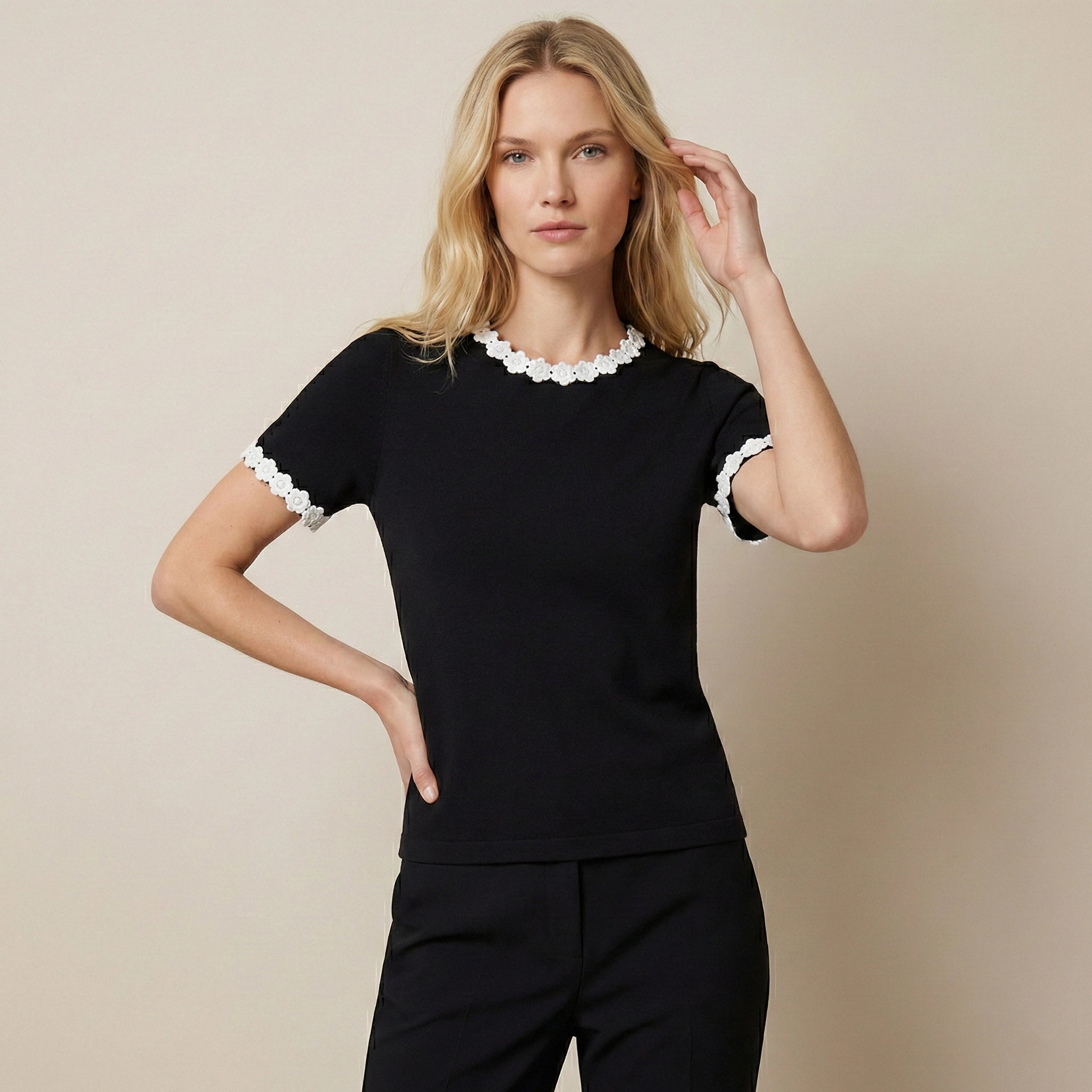 Woman wearing a black top with white lace trim on a beige background