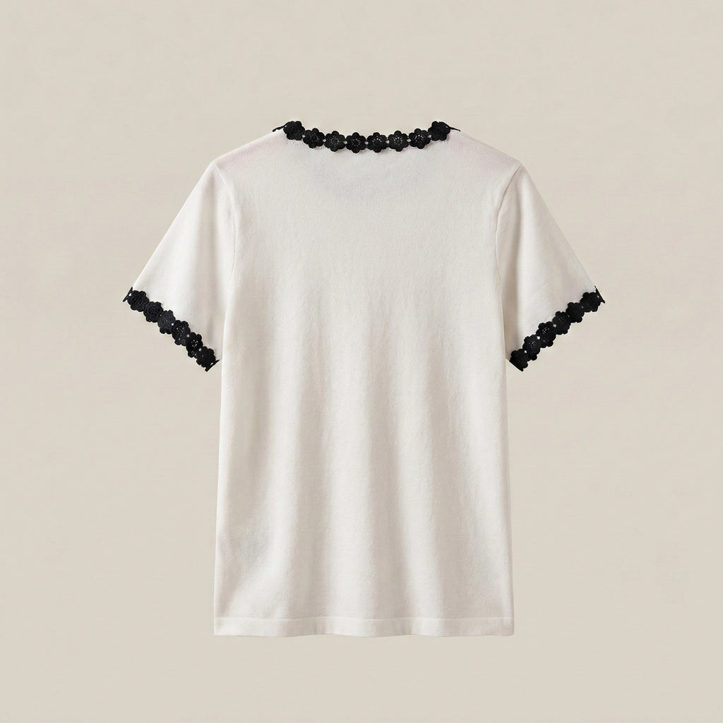 White t-shirt with black lace details on sleeves and neckline against a beige background