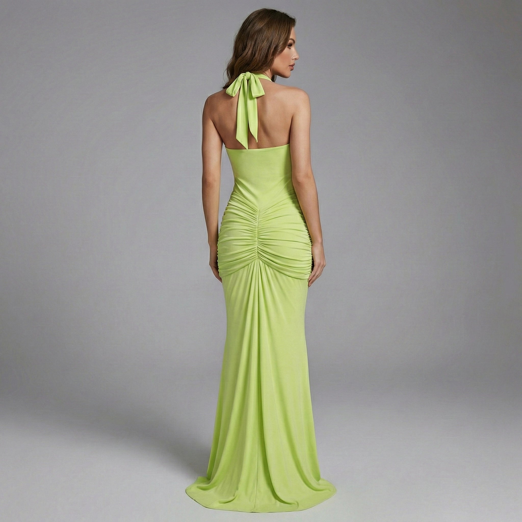 Woman wearing a green evening gown with a bow detail on a gray background