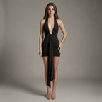 Woman wearing a black dress with a deep neckline on a plain background