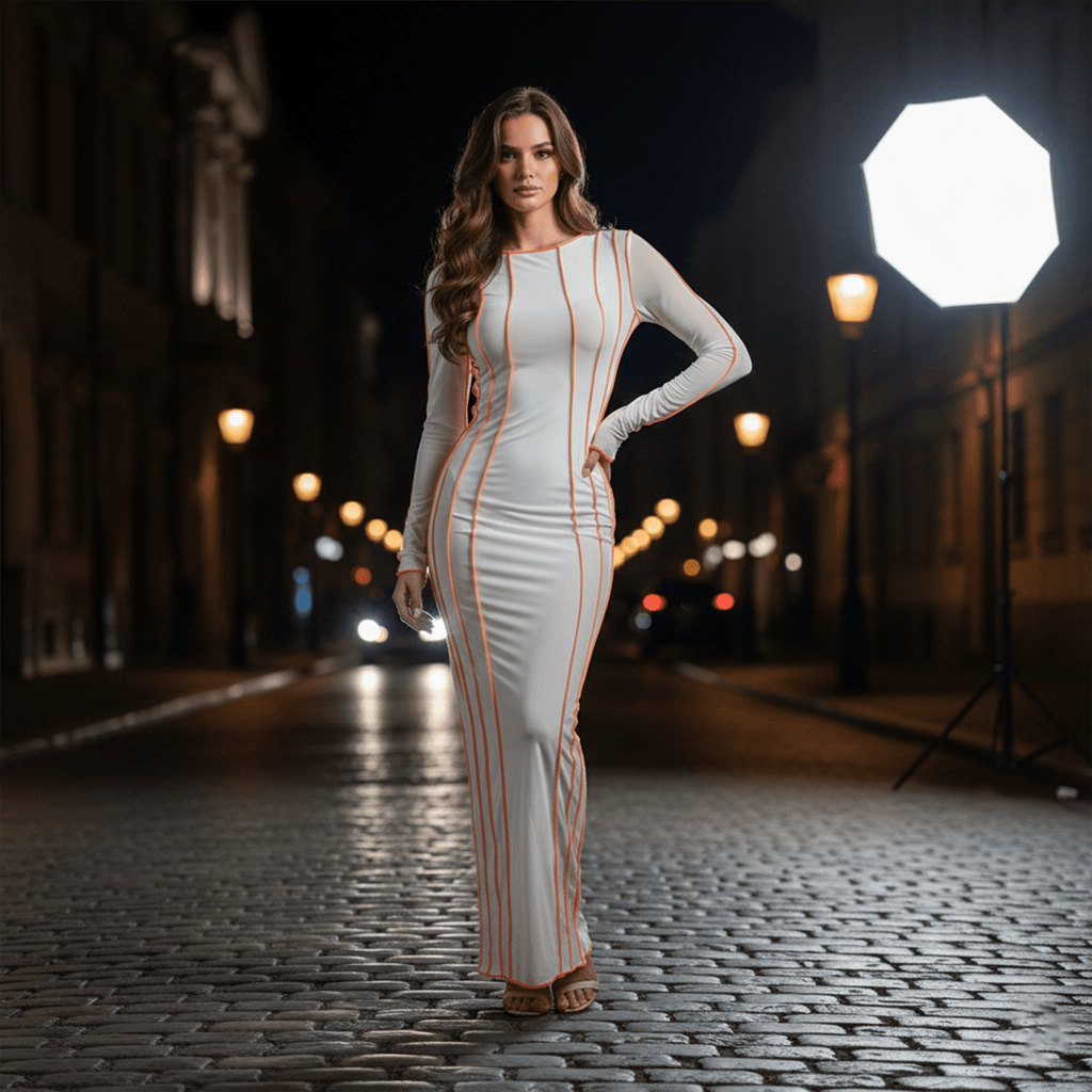 Woman in a white dress with red accents standing on a city street at night.