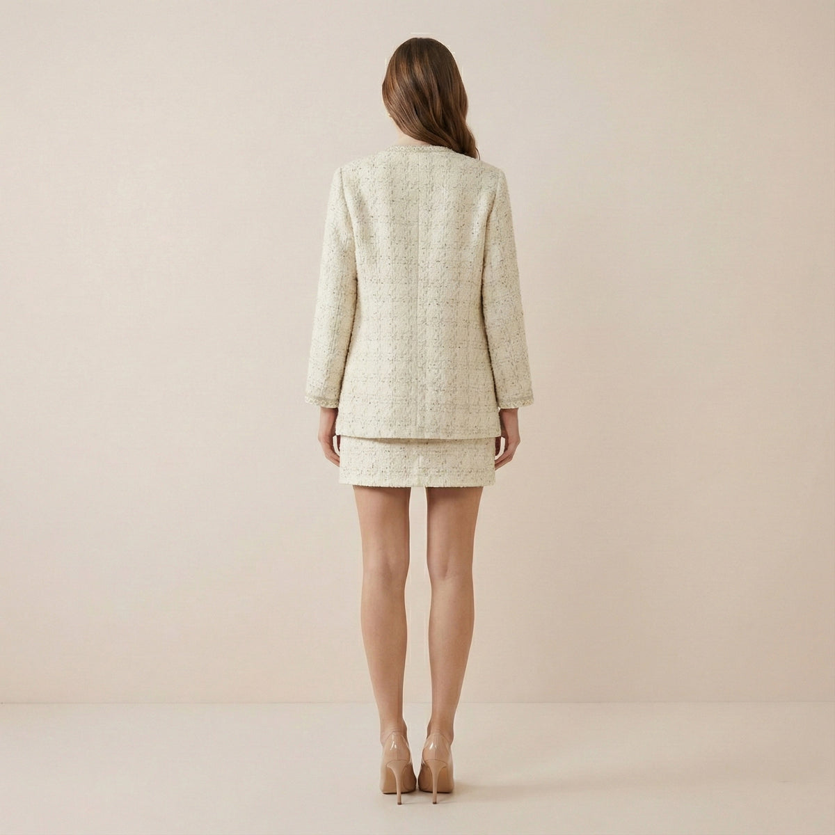 Woman wearing a beige suit standing against a plain background