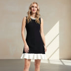 Woman wearing a black dress with a white hem on a gray background