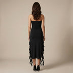 Woman wearing a black strapless dress with ruffled details on a beige background