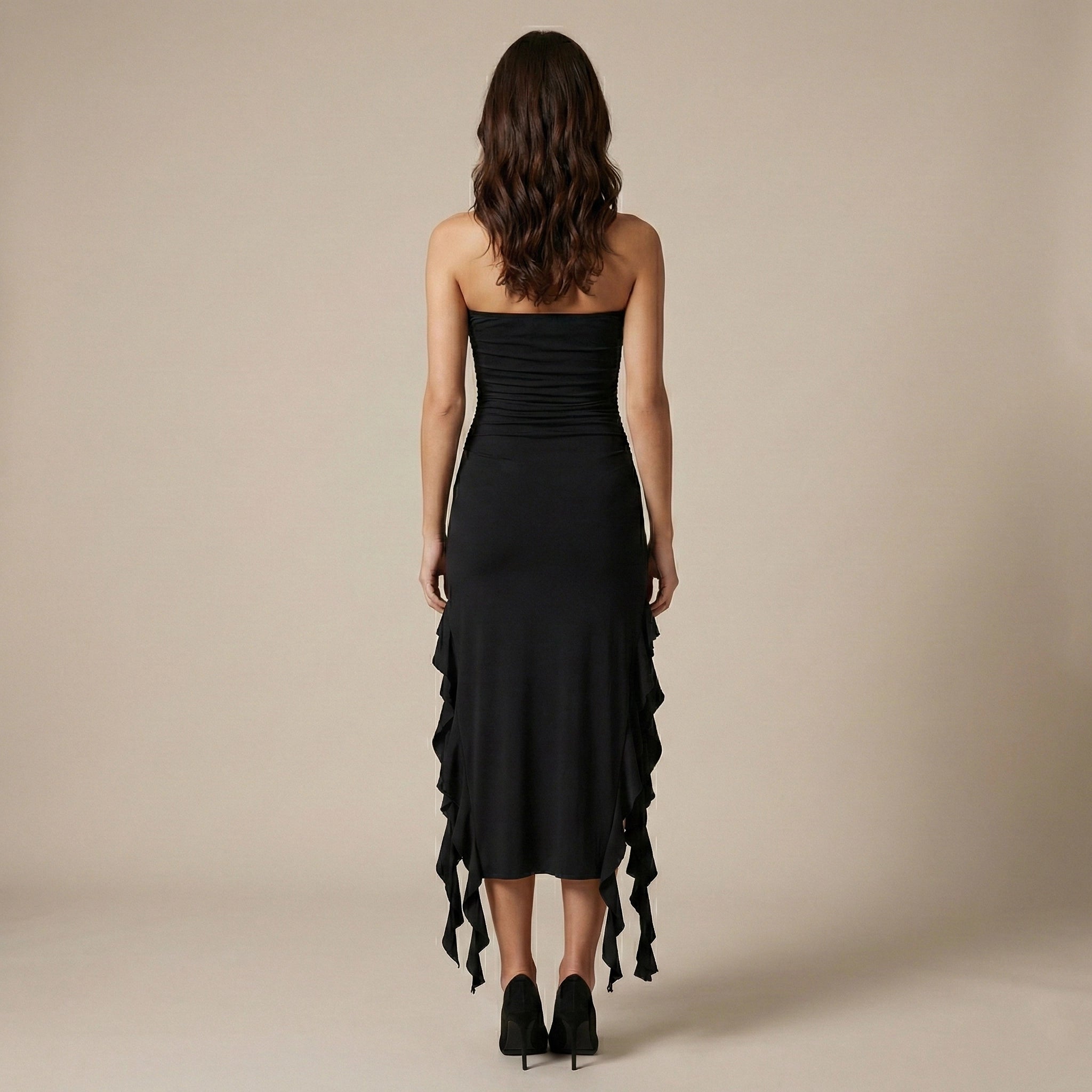 Woman wearing a black strapless dress with ruffled details on a beige background