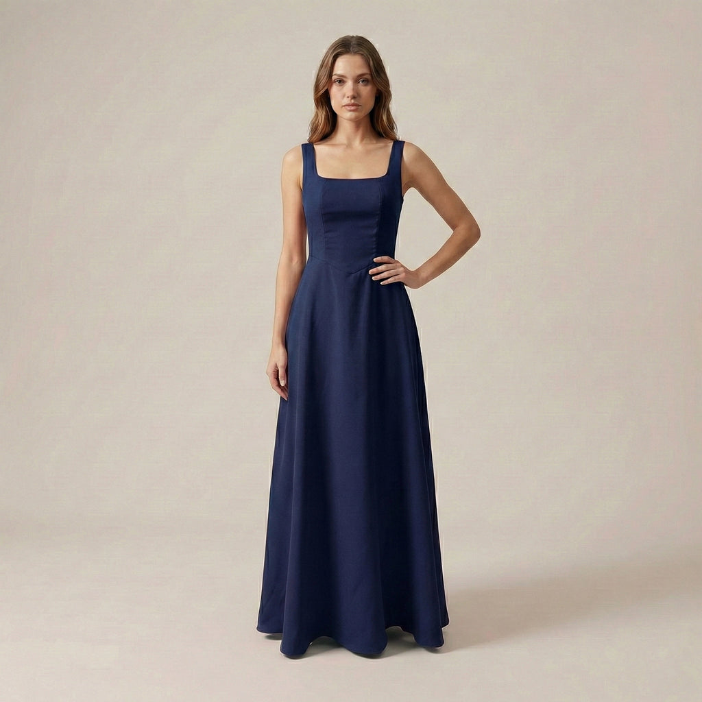Woman wearing a long navy dress against a plain background