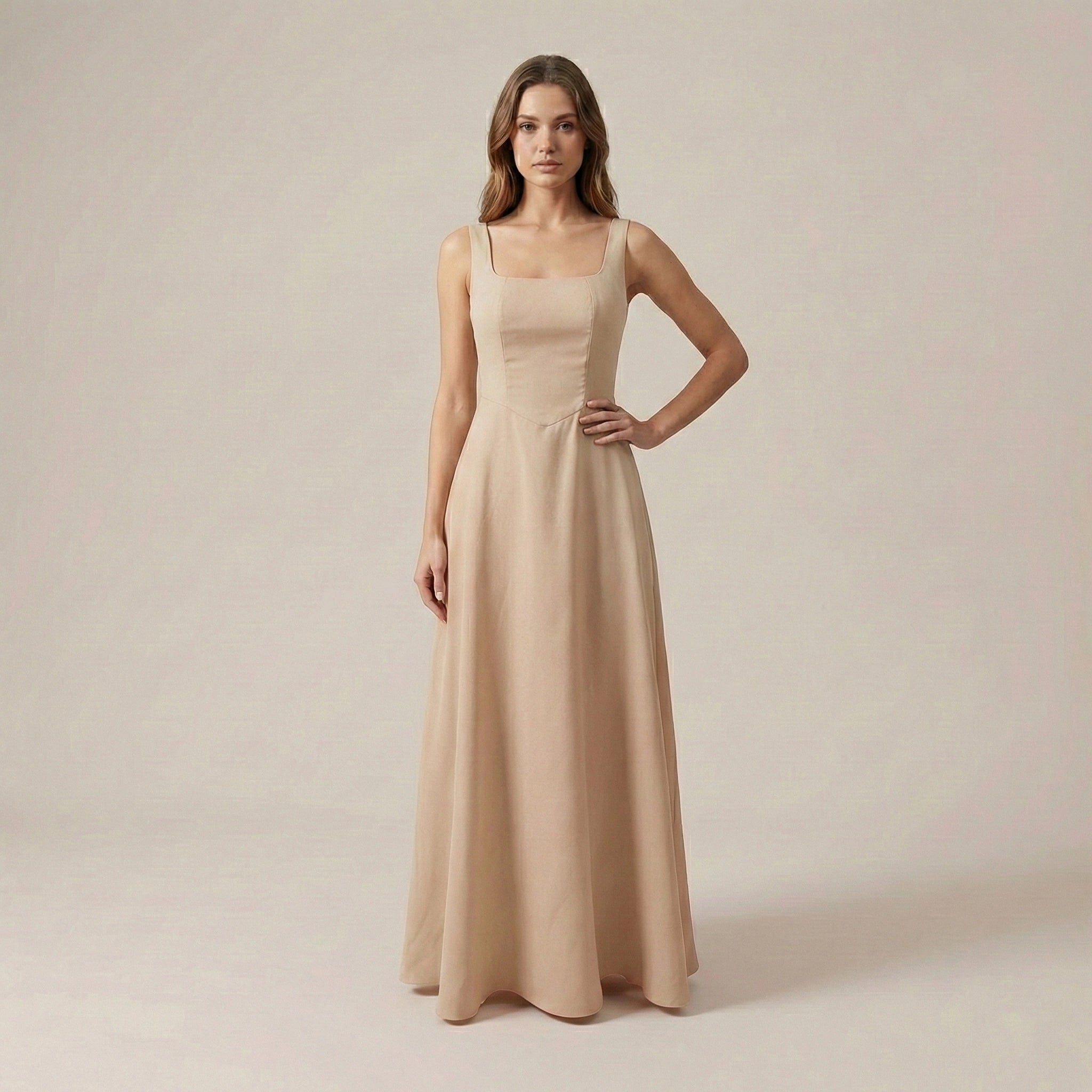 Woman wearing a beige sleeveless gown against a plain background