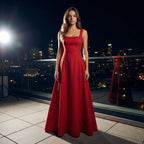 Woman in a red dress standing on a rooftop at night with city lights in the background