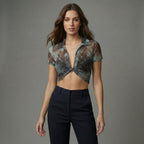 Woman wearing a patterned top and black pants against a gray background