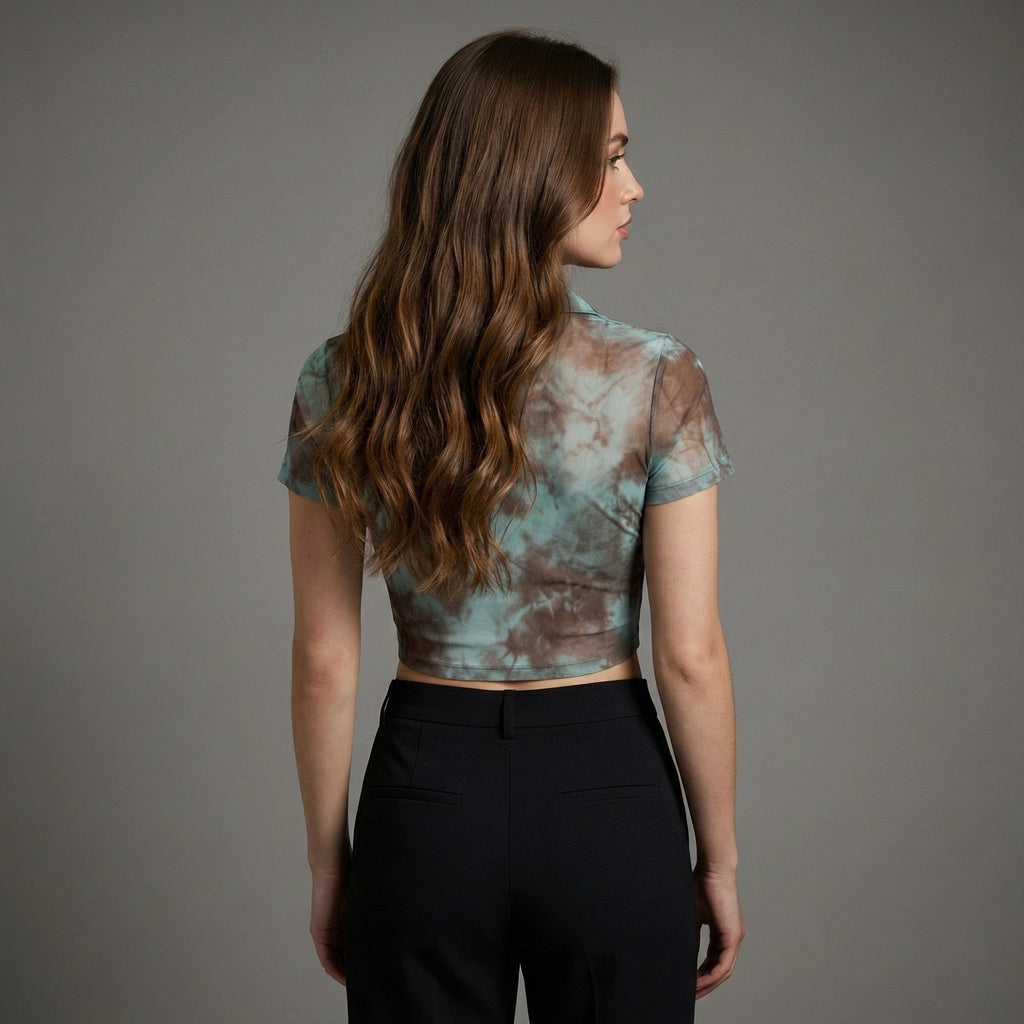 Woman wearing a tie-dye top and black pants against a gray background