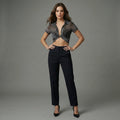 Woman wearing a sheer top and black pants against a gray background