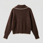 Brown sweater with white trim on a light gray background