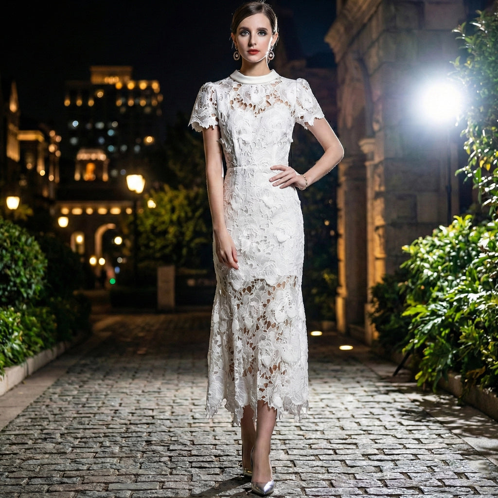 Woman in a white lace dress standing on a cobblestone street at night.