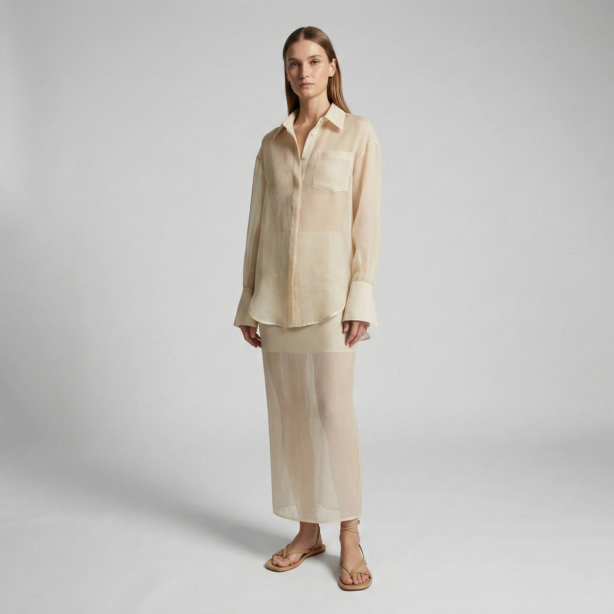 Woman wearing a beige shirt and pants on a plain background